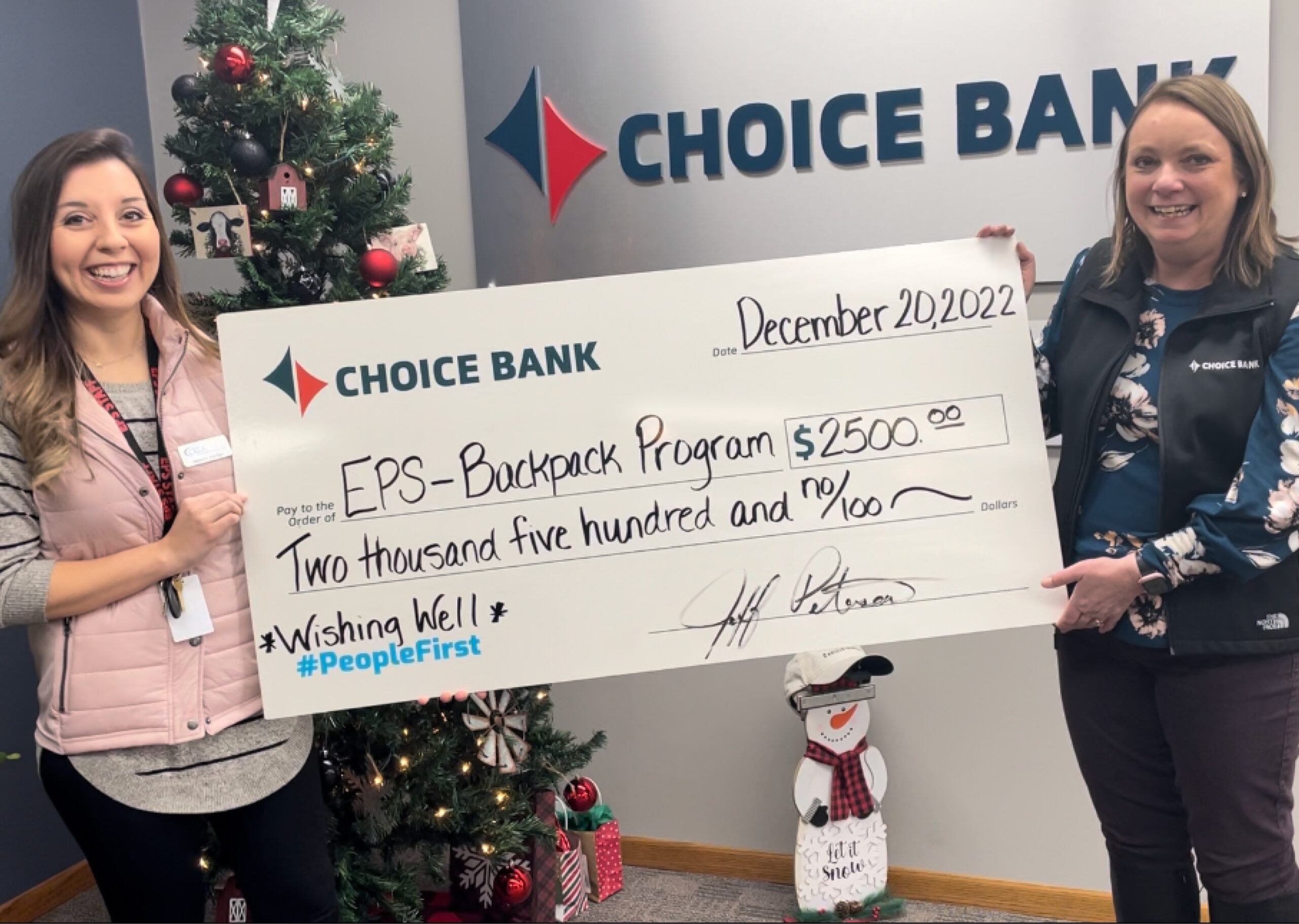 two women hold giant donation check