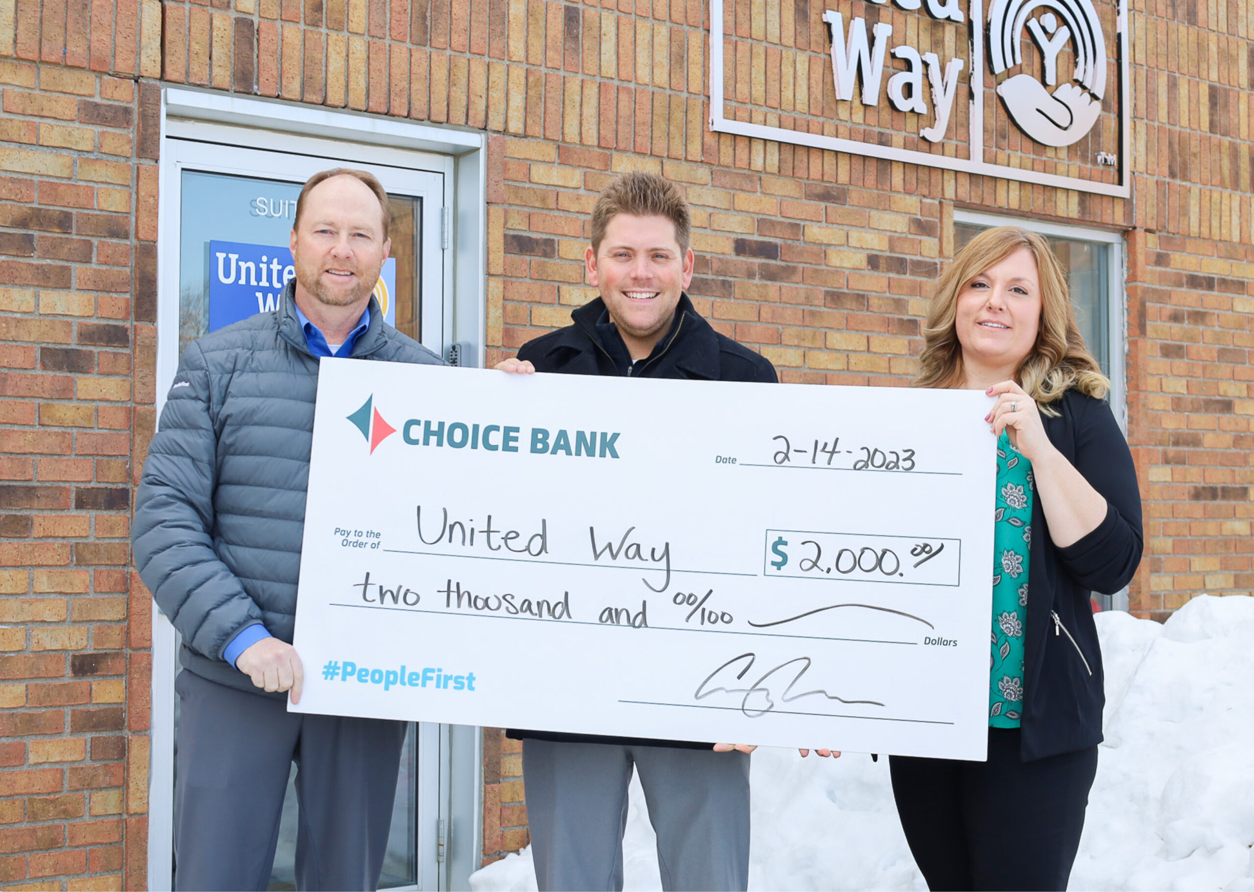 two men and a woman hold a large donation check