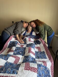 woman in hospice bed getting hugged by her children