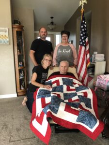 man with quilt smiling with family