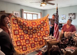man holds up quilt