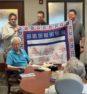 man poses with quilt