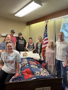 man poses with quilt and family