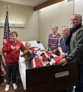 man poses with family after pinning ceremony